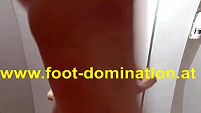 The redhead dominatrix stomps on her slave's feet, licking and sucking toes in a bdsm session.
