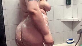 chubby tattooed beauty steps into the shower, teasing her big ass and shaved pussy
