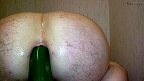 Gay man uses vegetable toy in ass during shower bath.