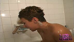 Tanned brunette with short hair shaves her long legs in the shower