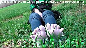 goddess feet in cute white socks with jeans on the spring grass field