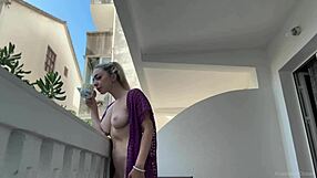 the blonde beauty strips naked on the balcony, flashing big tits and shaved pussy