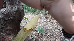 Perverted slut squirts piss from wooden stake in forest